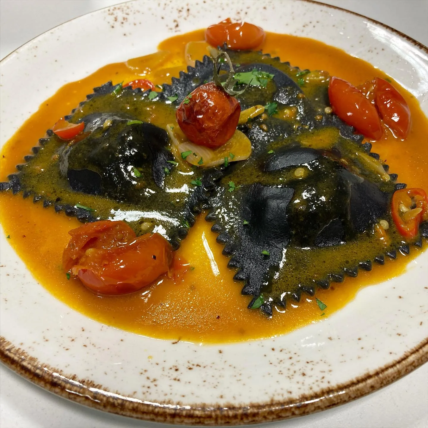Black ravioli in a bright tomato sauce